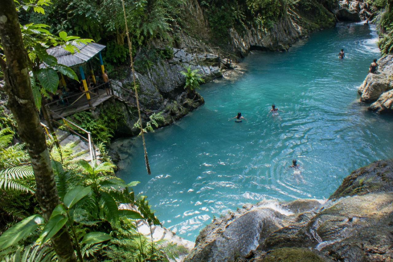 Turquoise lagoon pool at a jungle waterfall surrounded by ferns and limestone rocks