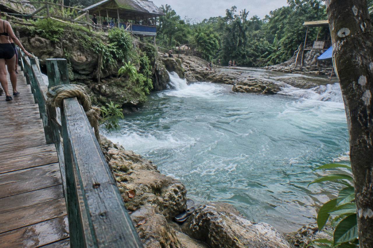 Turquoise waterfall pool surrounded by dense green forest in the hills above Ocho Rios