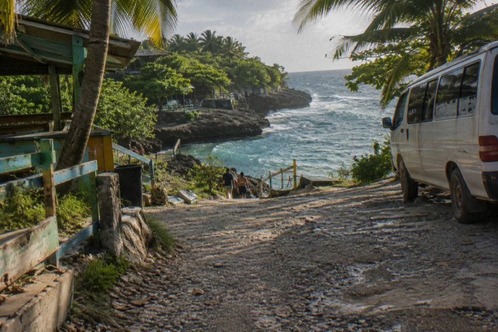 Coastal road winding along the shoreline with palm trees and turquoise sea