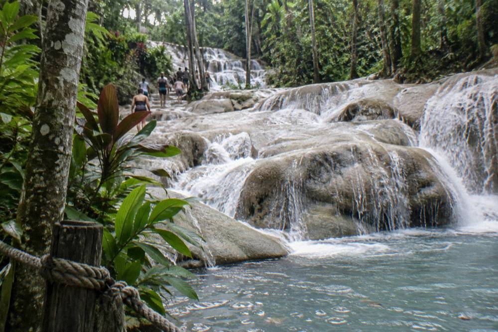 Waterfall cascading over limestone steps into a blue pool at Dunn's River Falls