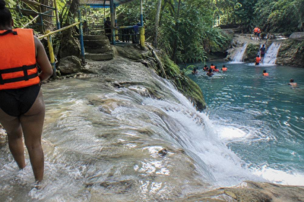 Chain of visitors holding hands while crossing a shallow limestone waterfall step