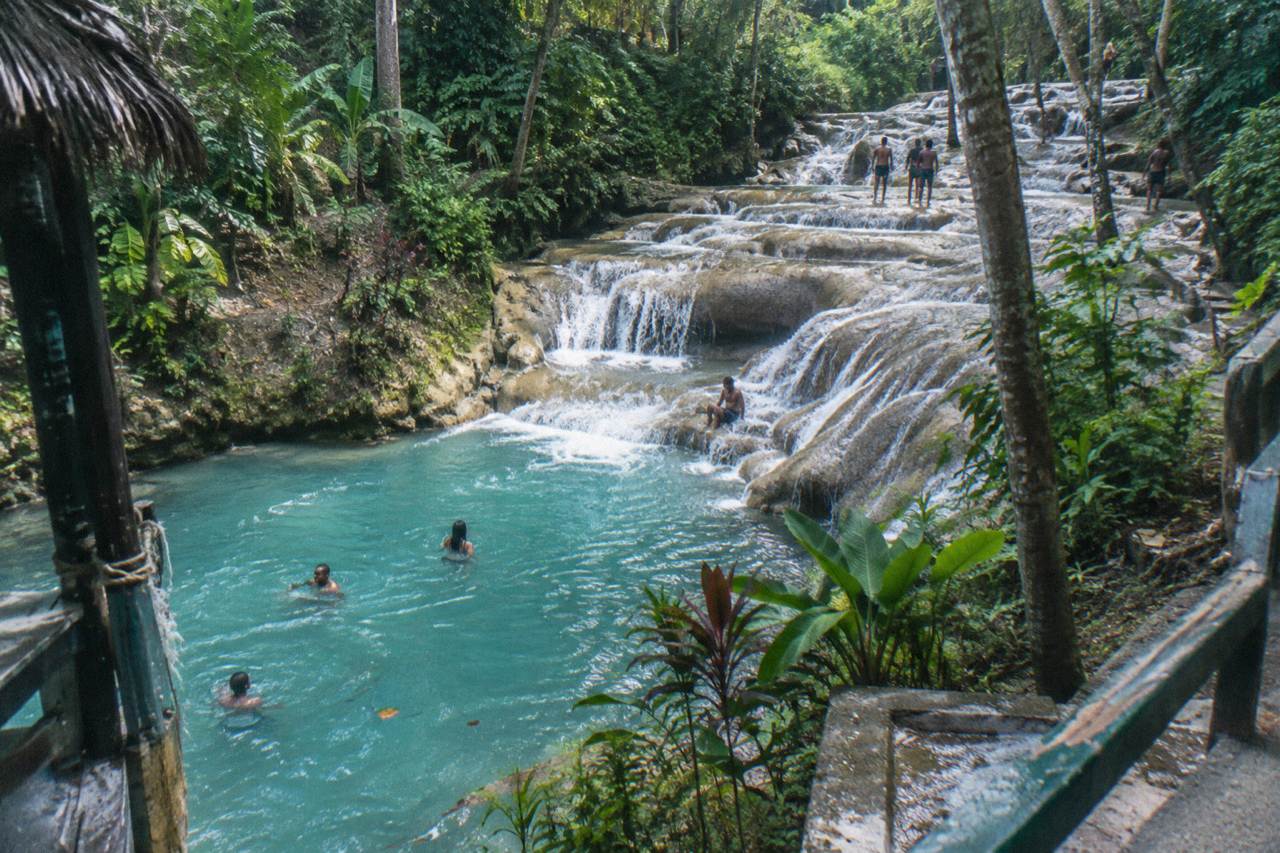 Terraced limestone waterfall cascading into a turquoise pool surrounded by tropical forest