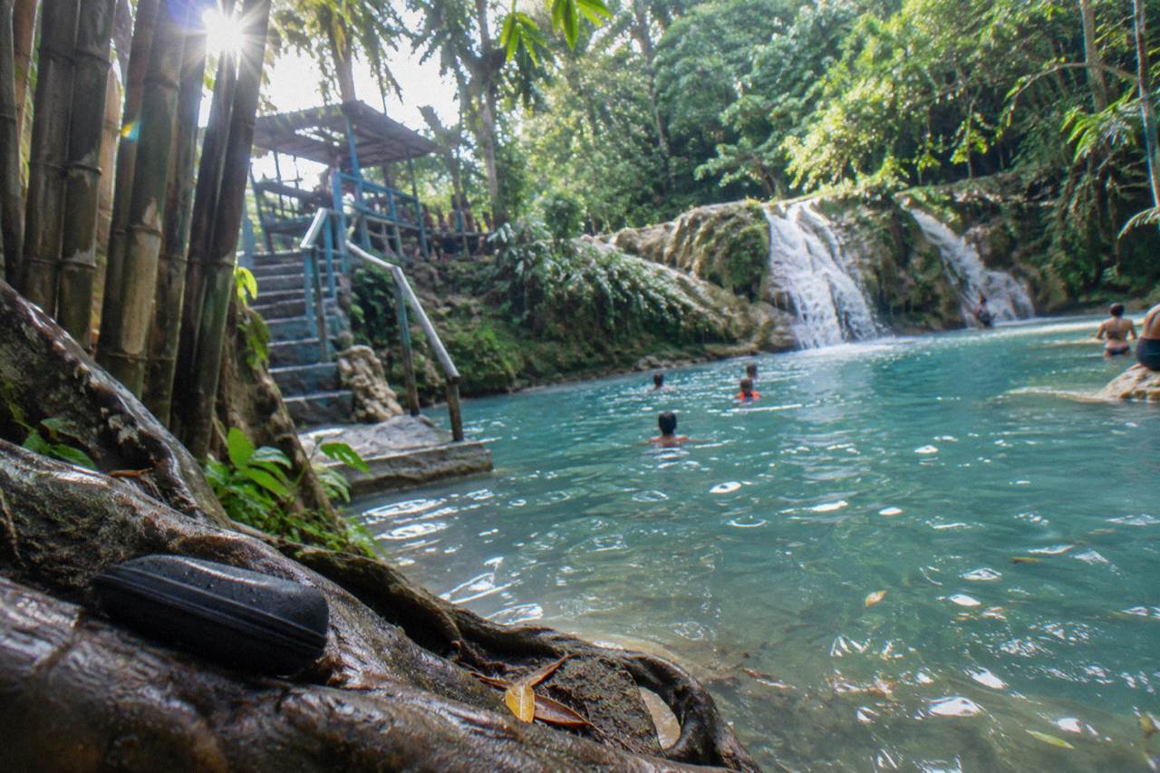 Turquoise waterfall pool at the Blue Hole surrounded by dense green forest