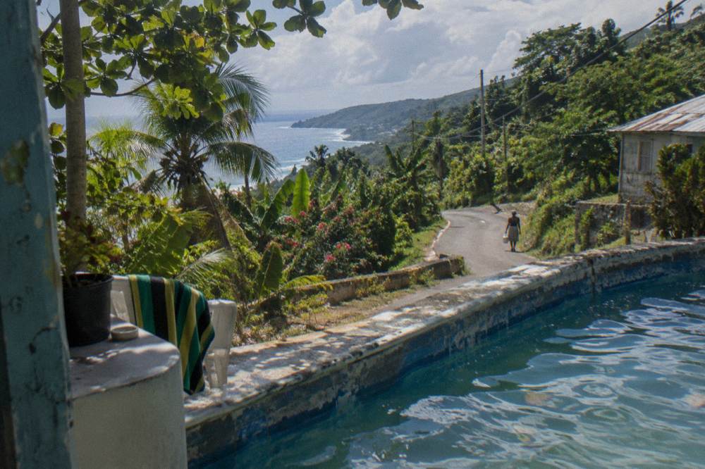 Winding mountain road with tropical vegetation under a bright sky in rural Jamaica