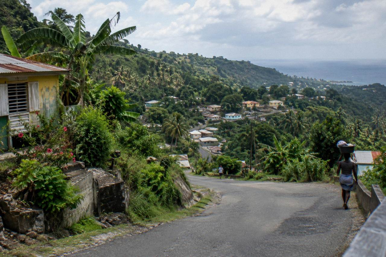 Mountain road winding through green hills toward a small Jamaica countryside village