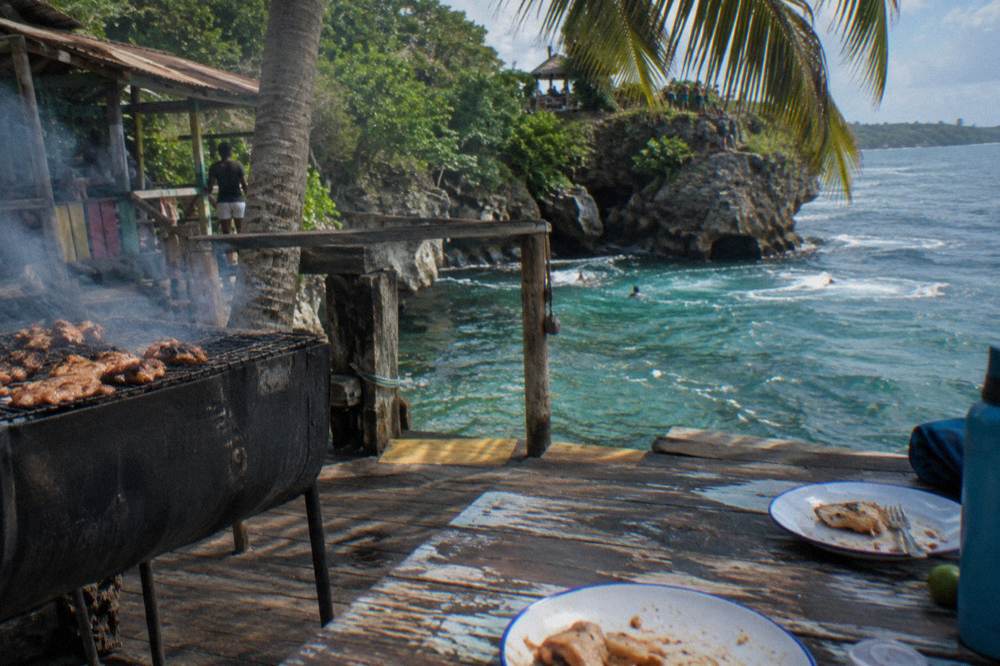 Open air restaurant serving jerk chicken beside a palm shaded patio