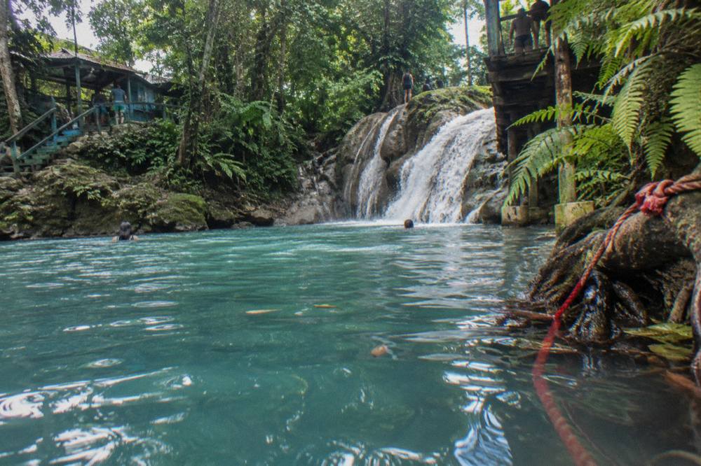Calm turquoise pool at a jungle waterfall with sunlit water
