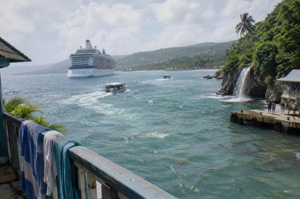 Cruise ship anchored off a green coastline with tenders heading to shore