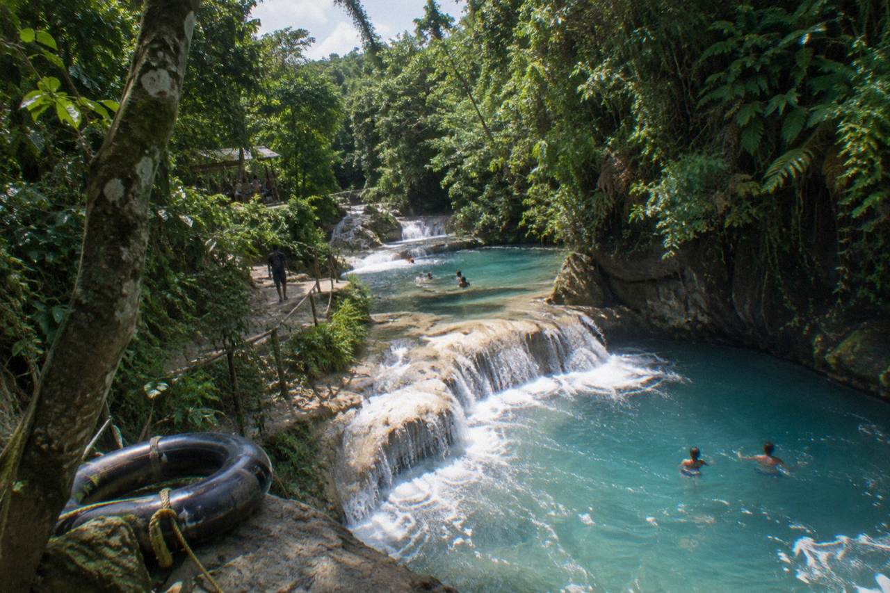 Turquoise waterfall pools surrounded by dense green forest near Ocho Rios