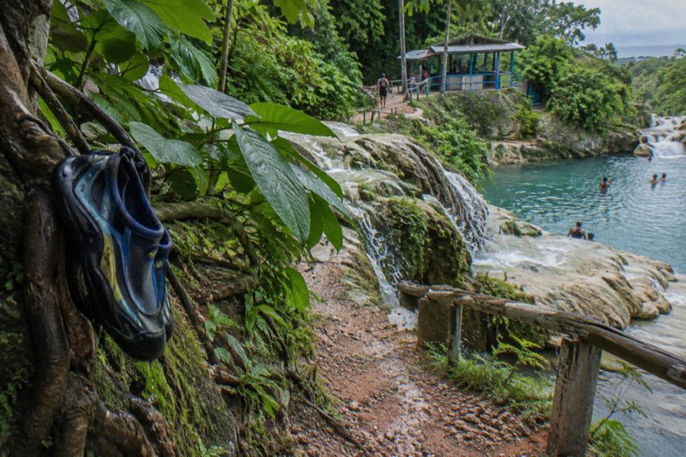 A jungle trail beside a series of small waterfalls cascading over limestone rocks