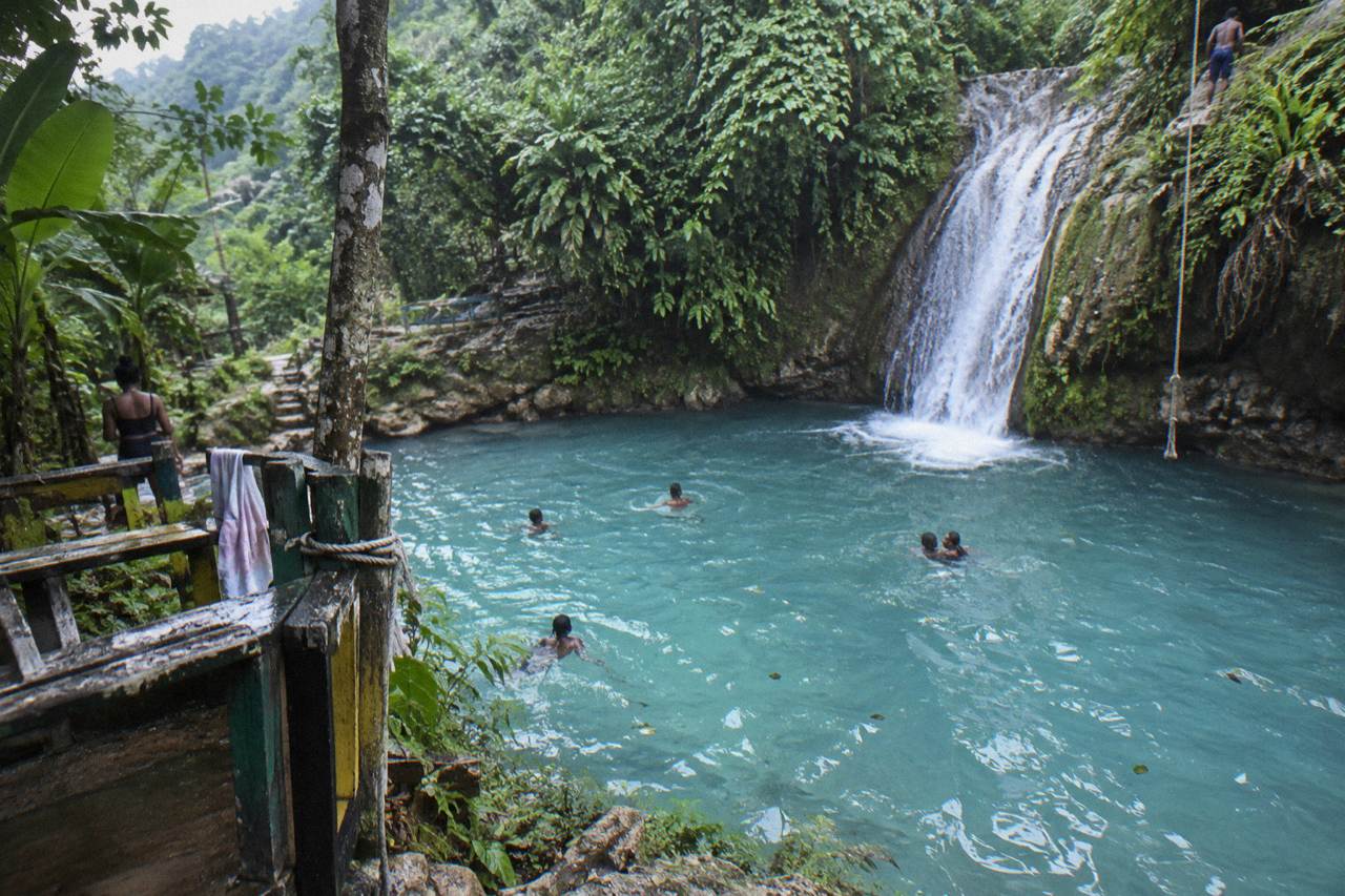 Turquoise waterfall pool ringed by jungle foliage in the hills above Ocho Rios