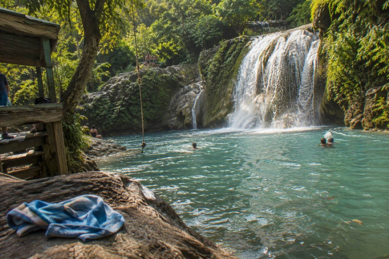 Turquoise waterfall pool surrounded by dense green jungle foliage in Jamaica