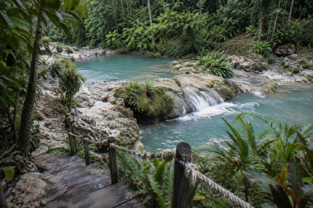 Turquoise jungle pool between limestone rocks and tropical trees