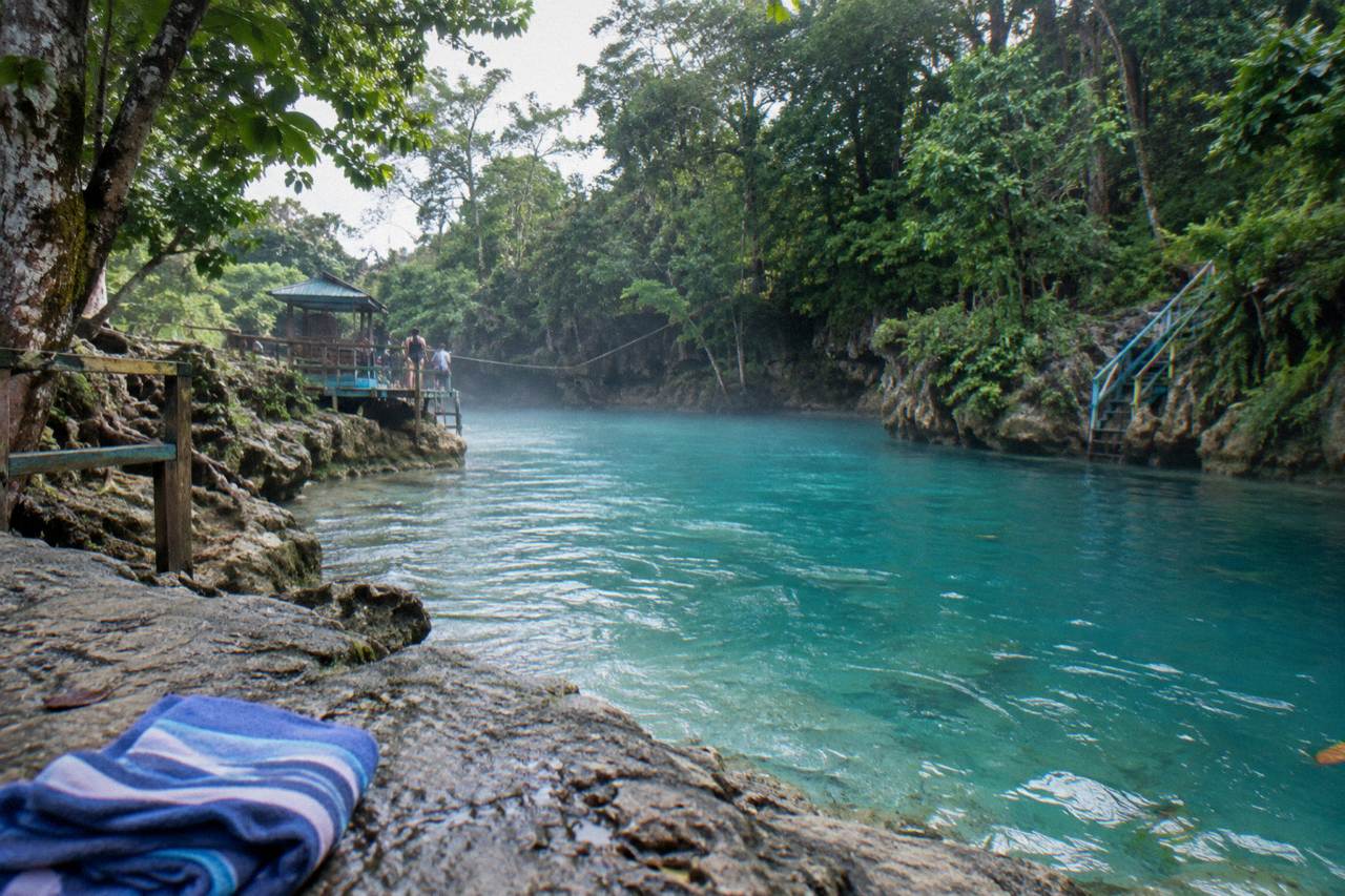 Turquoise pool at a jungle waterfall surrounded by dense green forest in Jamaica