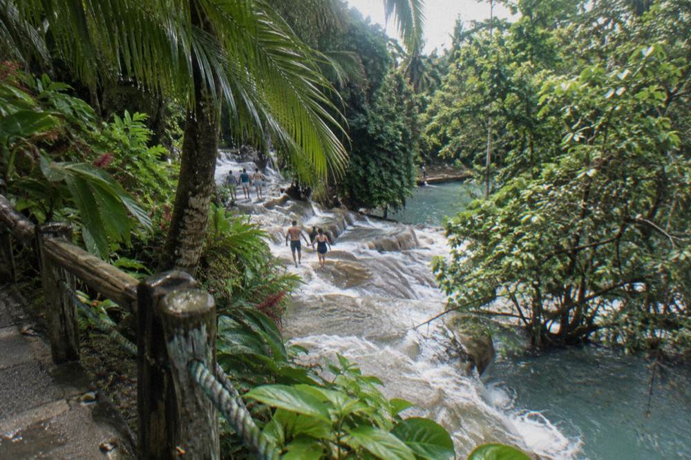 Visitors ascending a wide stepped waterfall in a line holding hands