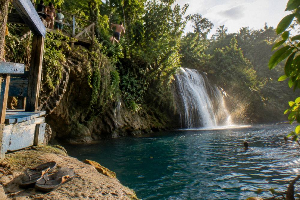 Swimmer mid-air between jungle canopy and a deep blue pool