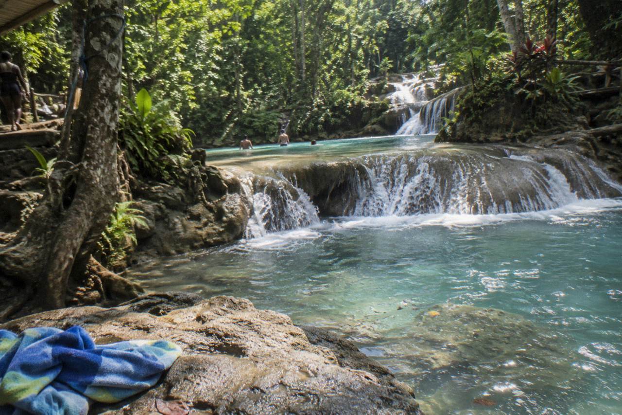 Turquoise waterfall pools surrounded by dense green forest near Ocho Rios