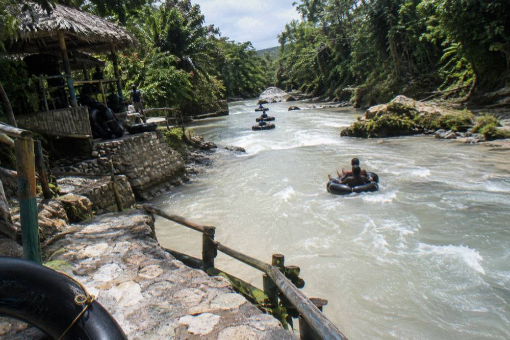 Inflatable tubes floating down a shallow river between forested banks