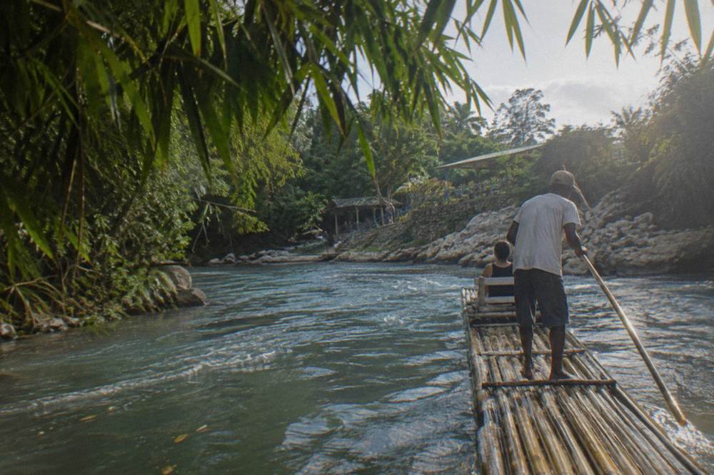 Two person bamboo raft poled by a captain along a quiet jungle river