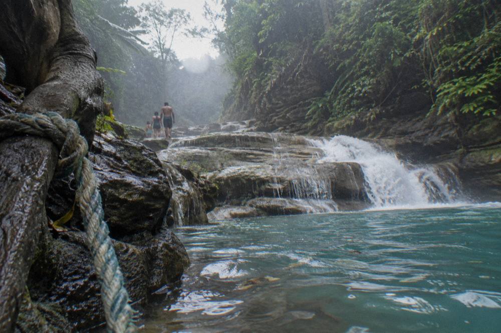 Narrow jungle river gorge with layered limestone cascades and clear blue water