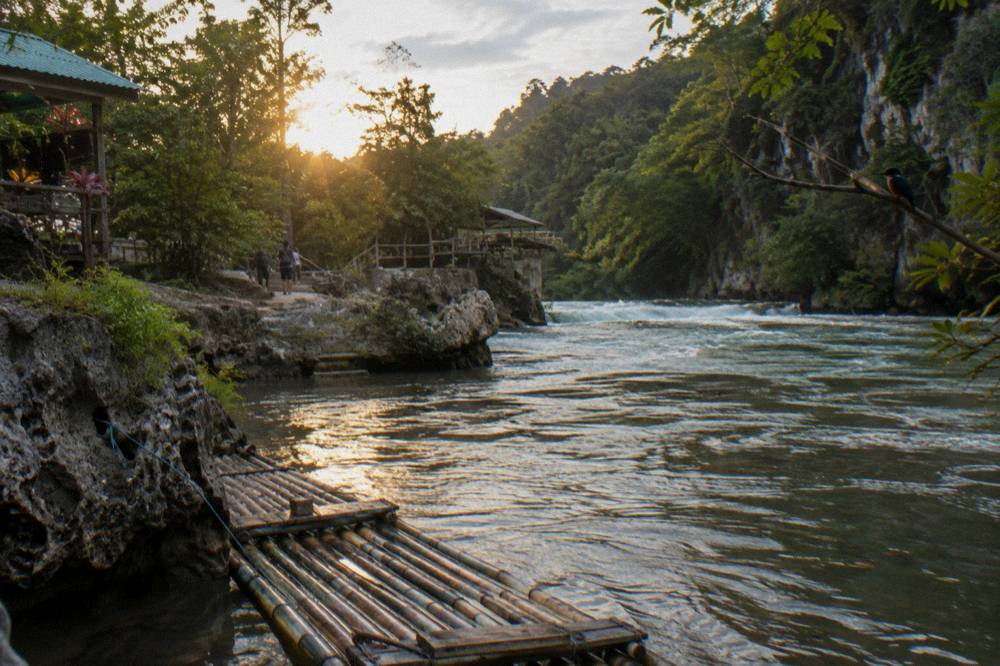 Bamboo raft drifting along a calm jungle river at golden hour