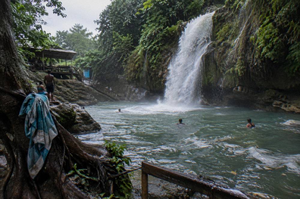 Waterfall pool after rain, water running faster and darker under overcast sky