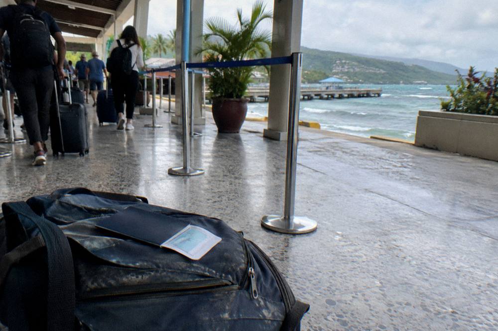 Passport and boarding pass resting on a daypack beside a cruise terminal