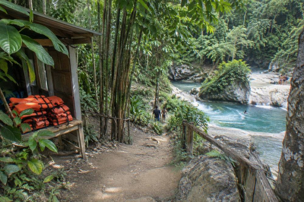 Rainforest river gorge with a turquoise pool and falls near the Blue Hole entrance