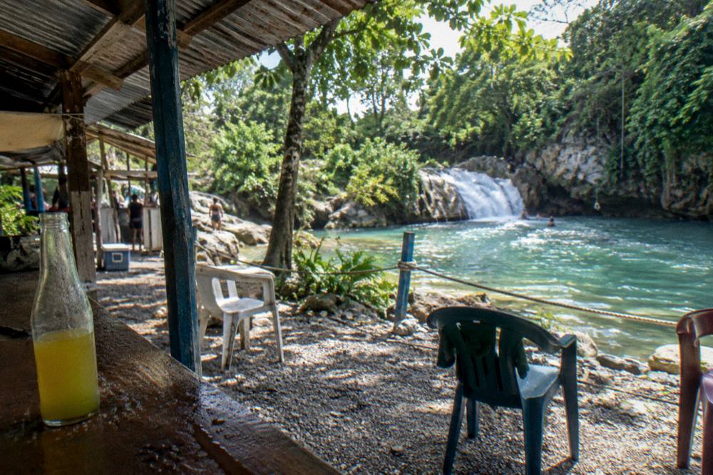 Snack bar and shaded seating area beside a Jamaican waterfall attraction