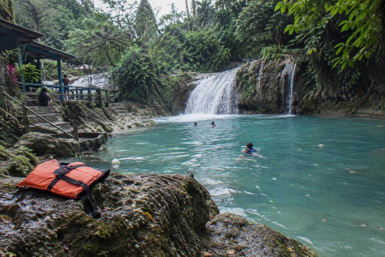 Turquoise waterfall pool at the Blue Hole surrounded by green forest