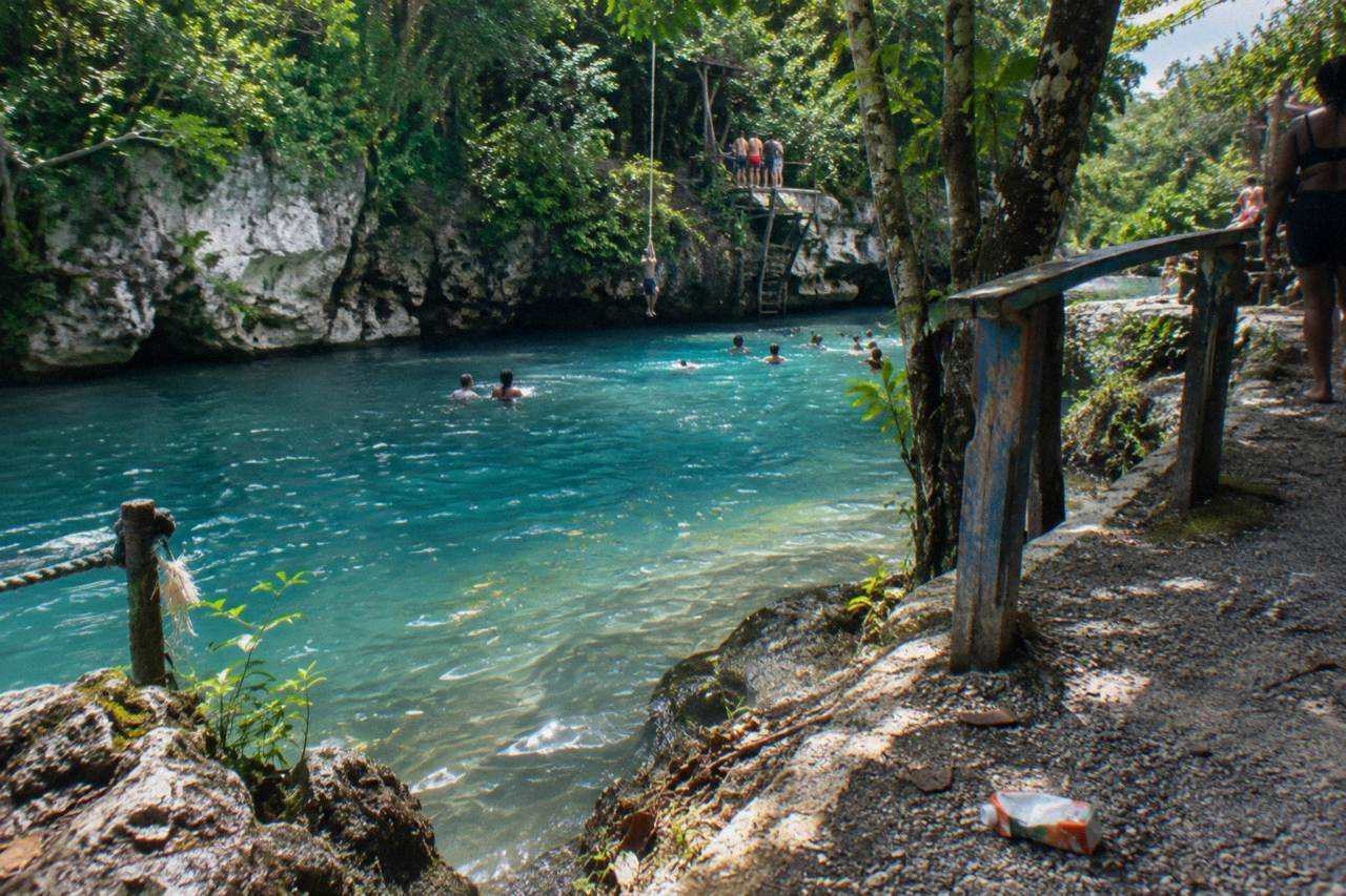 Turquoise pool of a jungle waterfall surrounded by limestone rock and dense green forest