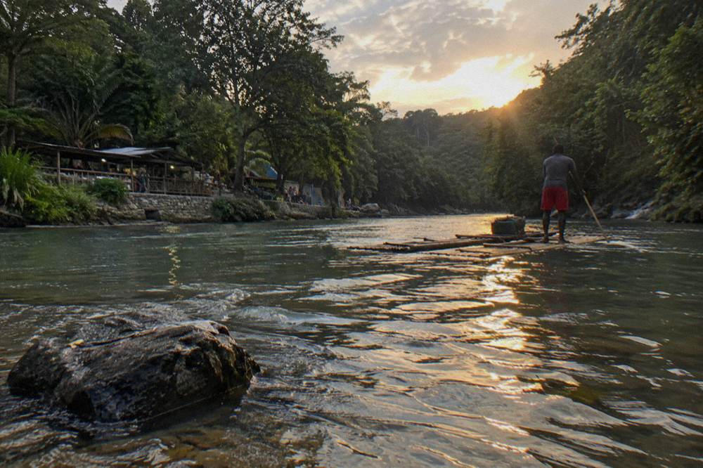 Bamboo raft drifting on a calm green river between overhanging trees