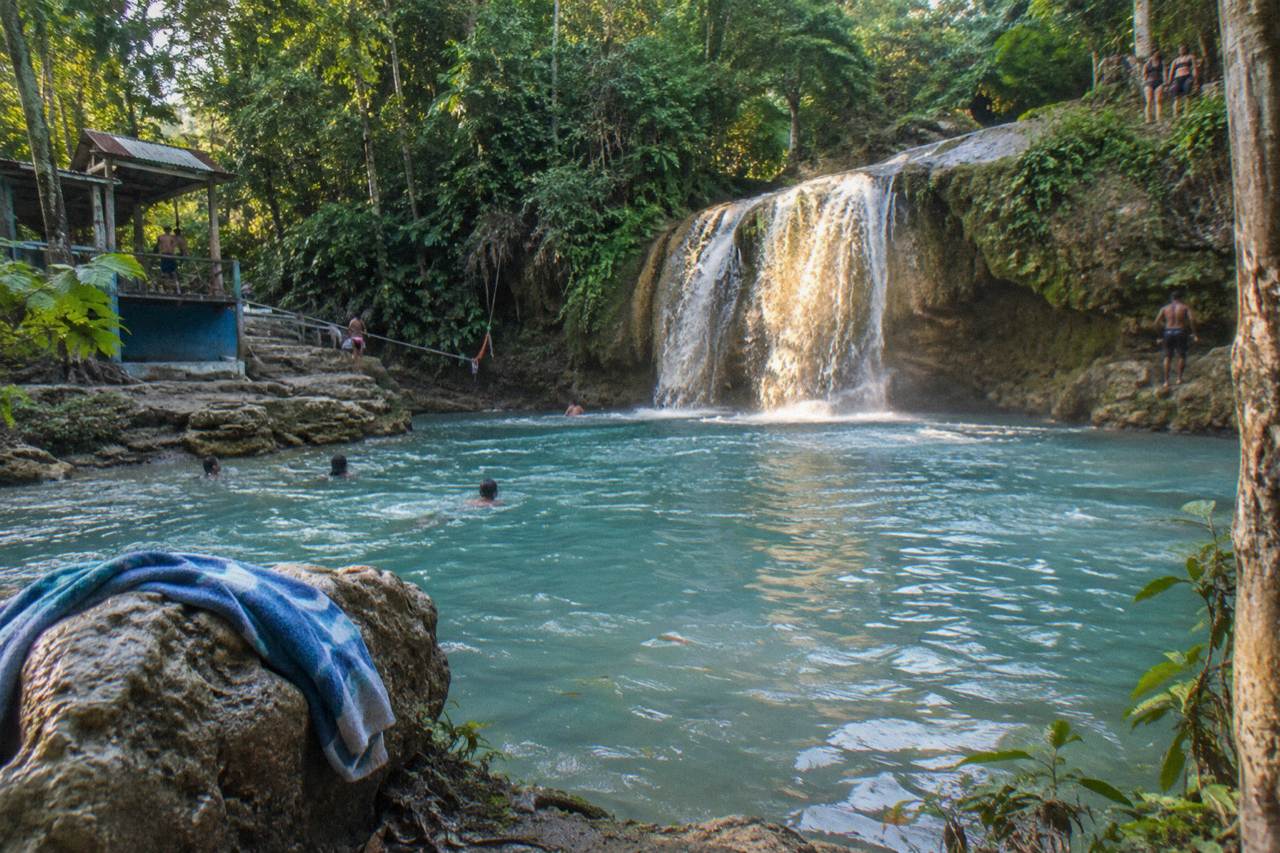 Turquoise pool at a jungle waterfall surrounded by limestone rocks and dense green forest