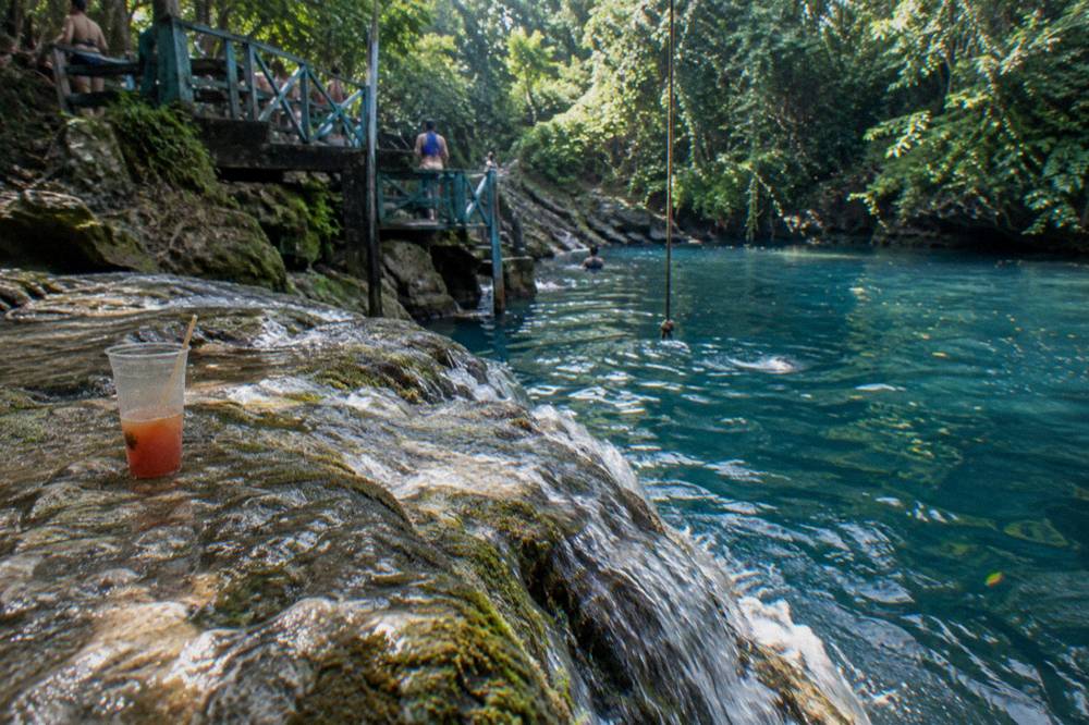Sunlight falling on a cascade of water into a deep blue jungle pool in the morning