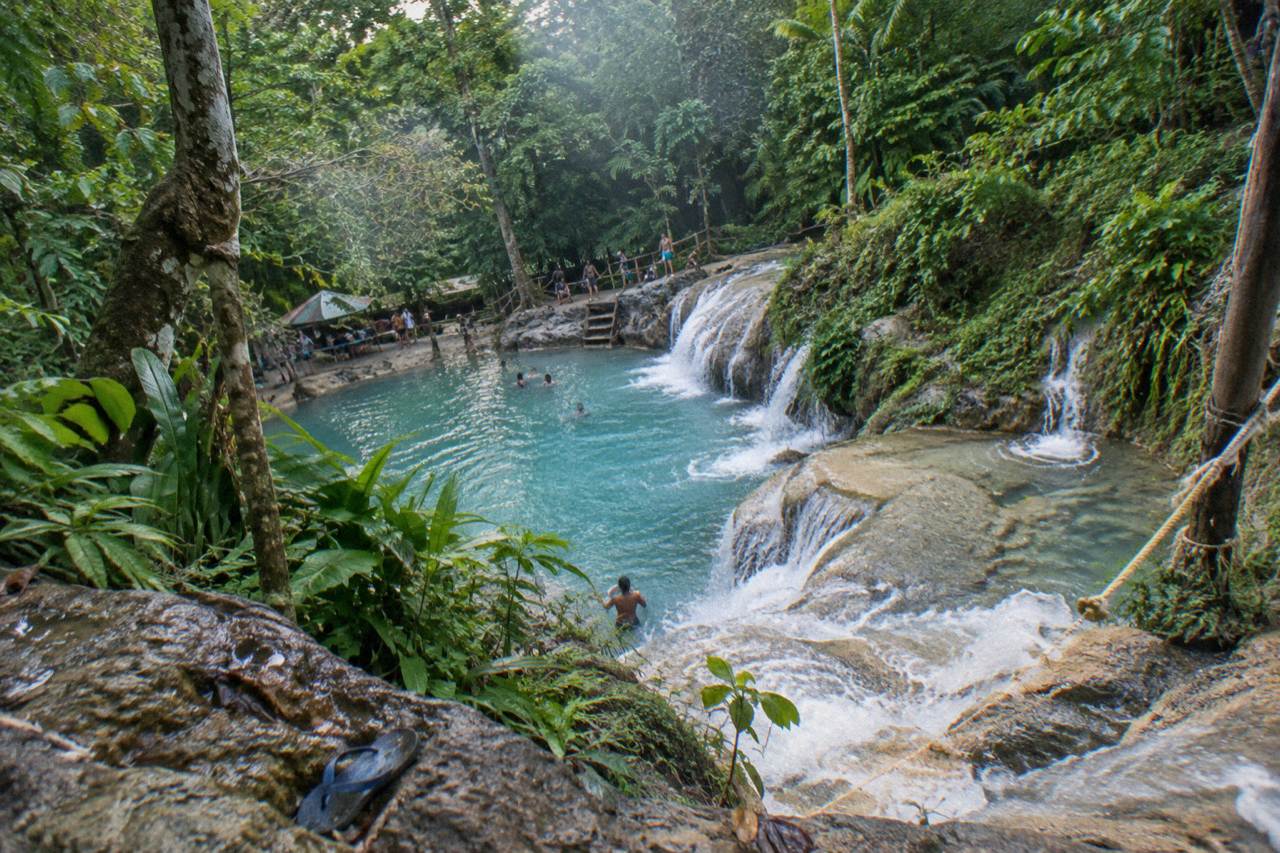 Turquoise waterfall pool surrounded by dense jungle foliage near Ocho Rios