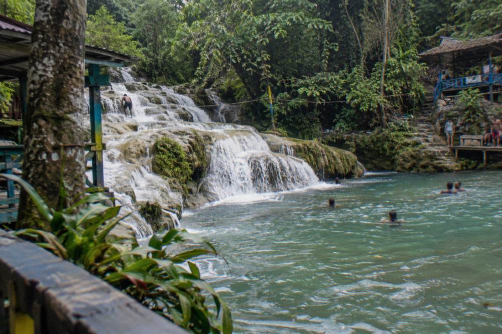 Waterfall cascading over limestone terraces into a pool at a Jamaican falls attraction
