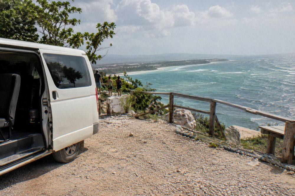 Tour van parked on a roadside lookout above the Caribbean coastline