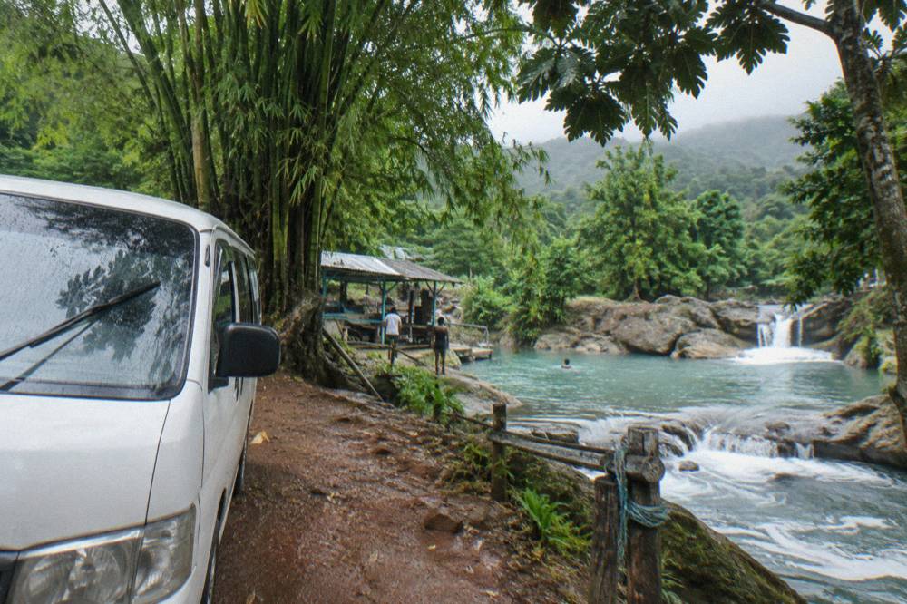 Private tour vehicle parked on a jungle road near a waterfall entrance in Jamaica