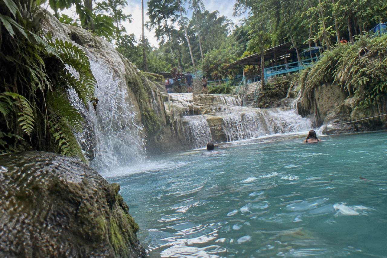Turquoise waterfall pool surrounded by dense green forest at the Blue Hole near Ocho Rios