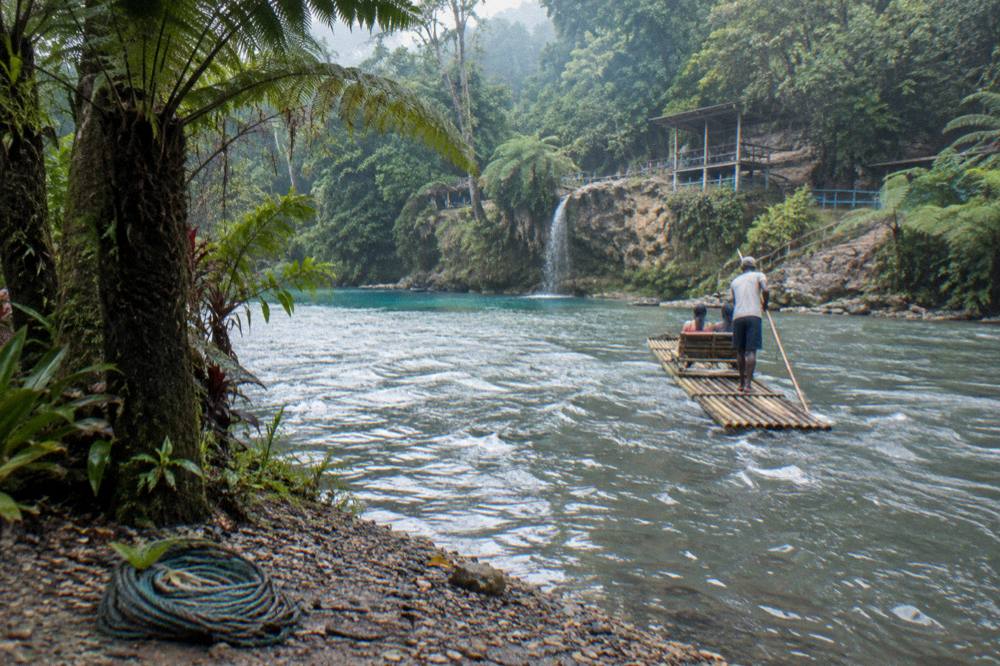 Bamboo raft floating on a calm jungle river between green banks
