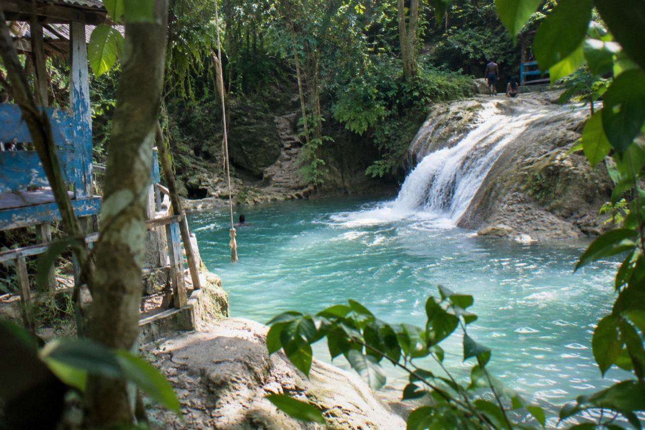 Turquoise waterfall pool surrounded by lush green jungle foliage in Jamaica