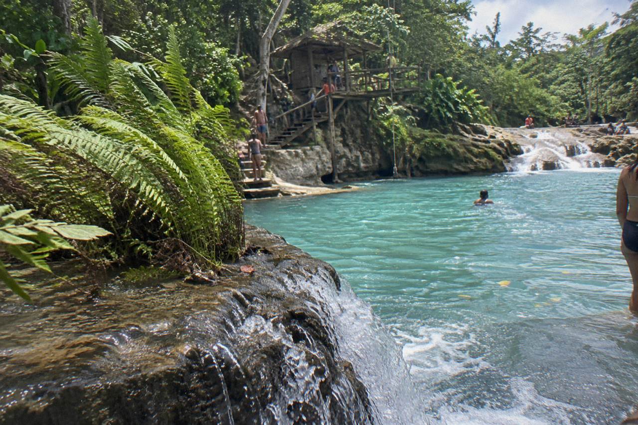 Turquoise pool of a jungle waterfall ringed by limestone rocks and dense green trees