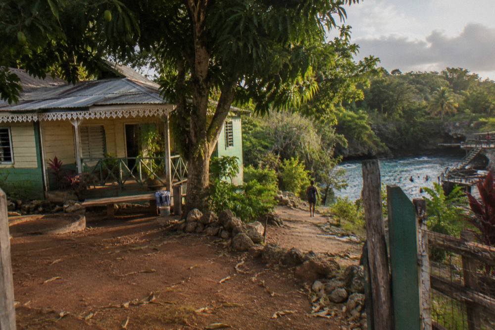 Small hillside house surrounded by tropical trees in rural Jamaica