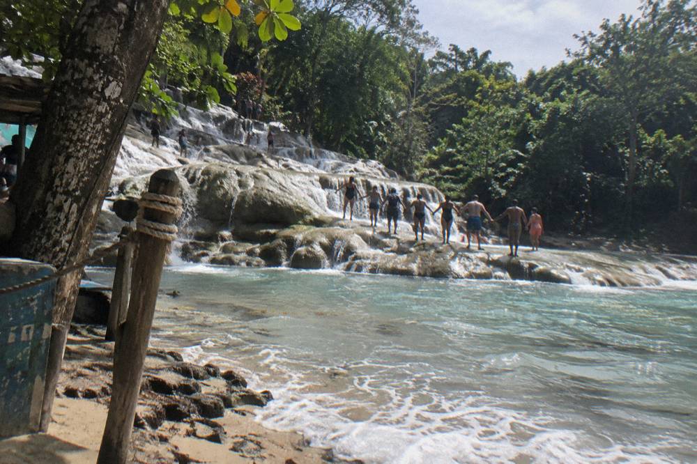 Tour group climbing a waterfall in a line holding hands