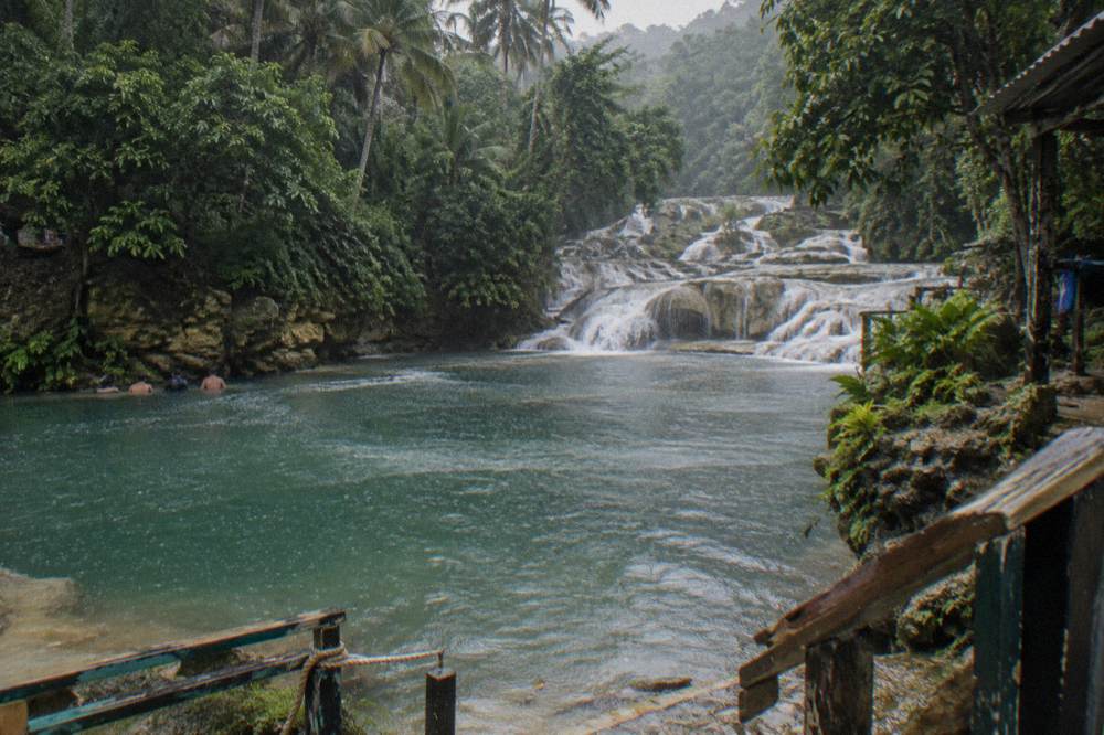 Turquoise waterfall pool ringed by green jungle foliage