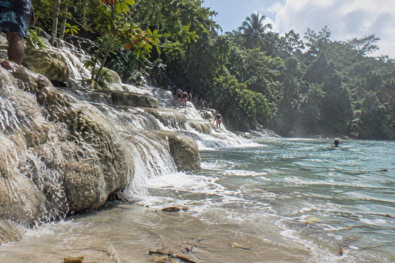Terraced limestone waterfall cascading into a blue pool surrounded by tropical forest