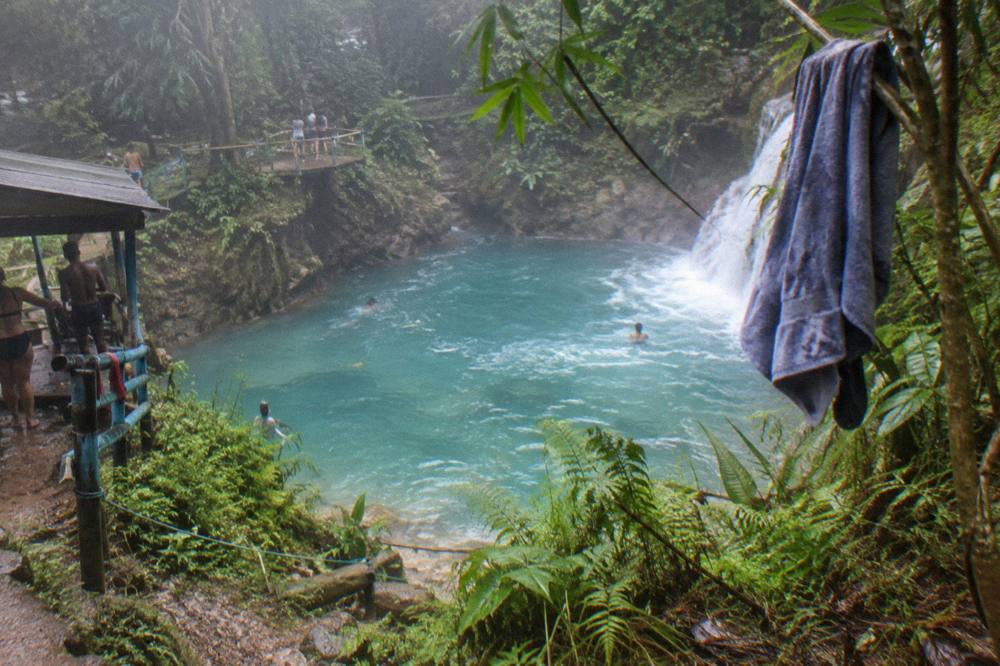 Turquoise waterfall pool surrounded by dense jungle foliage in morning light
