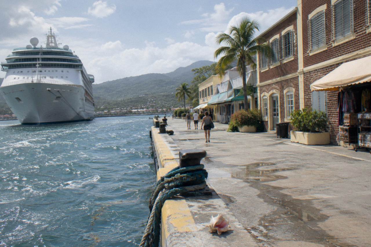 Cruise ship docked at a Caribbean port town with Georgian storefronts along the waterfront