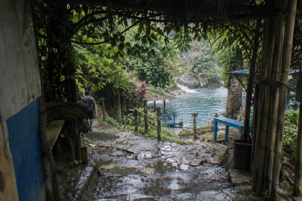 A narrow country road winding through green hills toward the waterfall site