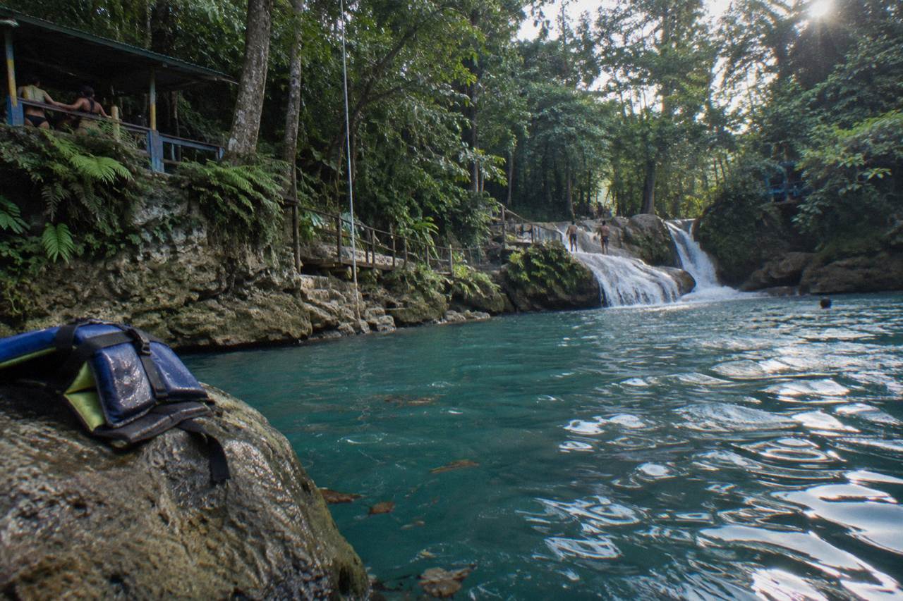 Turquoise waterfall pool framed by jungle vegetation at the Irie Blue Hole near Ocho Rios